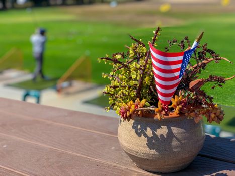 Patriotic flower pot with American flags and golfer on the background. American flag decoration.