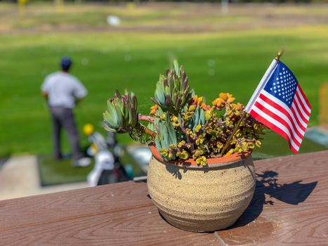 Patriotic flower pot with American flags and golfer on the background. American flag decoration.