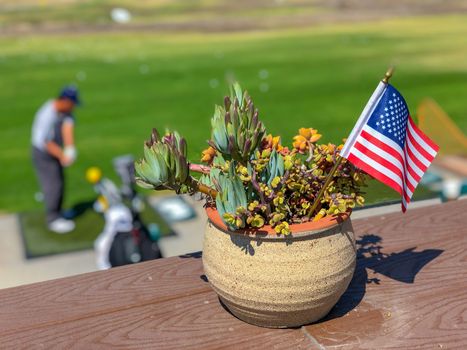 Patriotic flower pot with American flags and golfer on the background. American flag decoration.