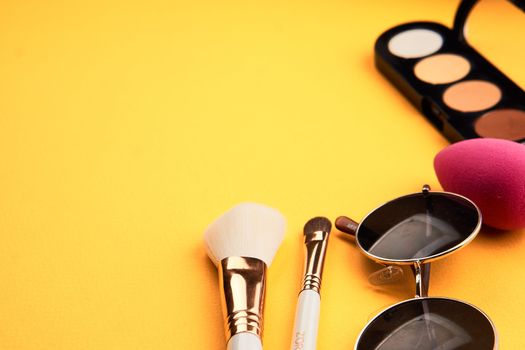 Eyeshadows on a yellow background professional cosmetics makeup brushes soft sponge fashion glasses. High quality photo