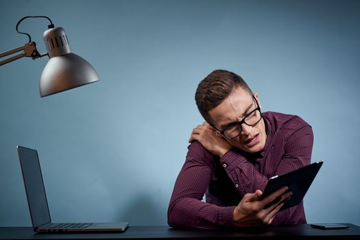 Male manager in the office with a tablet in his hand and a laptop on the table. High quality photo