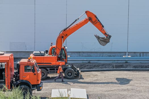 Foreman and large equipment, excavator and truck on site during construction