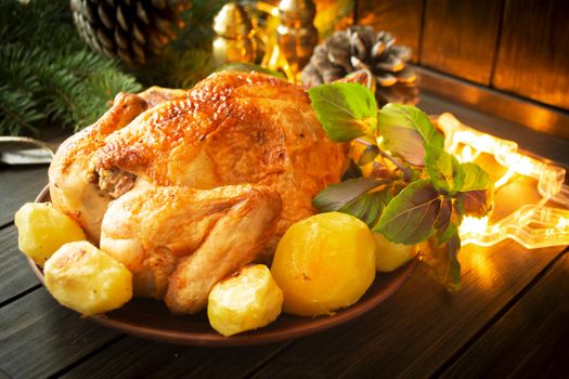 Homemade baked chicken with lemon, basil and potato on wooden background