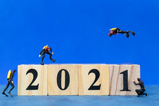 Miniature people divers diving around wooden block 2021 , Happy new Year concept