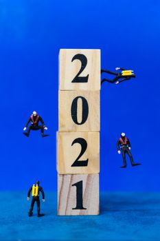 Miniature people divers diving around wooden block 2021 , Happy new Year concept