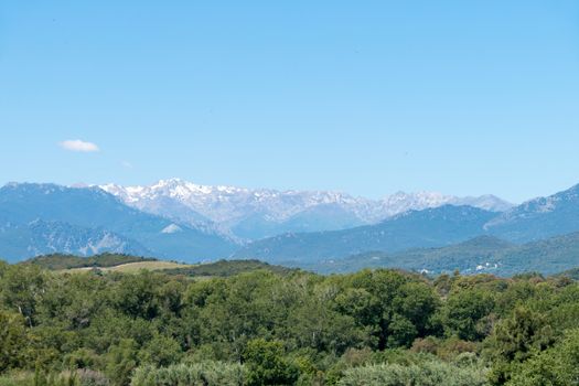 A landscape shot with green forests, mountains and a blue sky