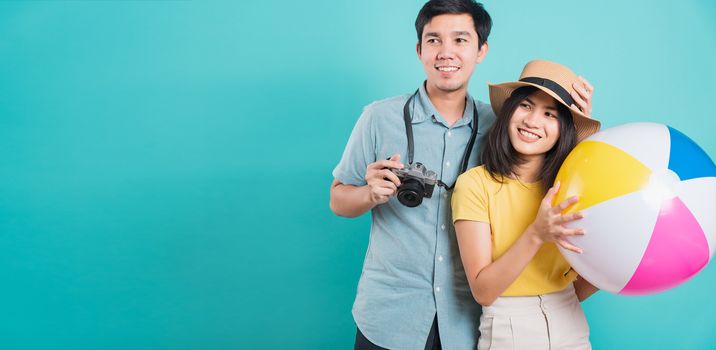 Happy Asian young beautiful woman handsome man couple in summer in holiday travel beach accessories ball and camera isolated on blue background with copy space for text