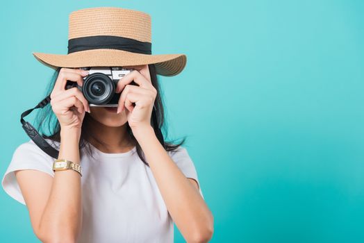 Traveler tourist happy Asian beautiful young woman smile in summer hat standing with mirrorless photo camera, shoot photo in studio on blue background with copy space for text