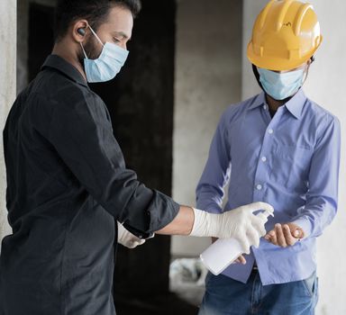 Poeple at construction site using Hand sanitizer before entering to work place as covid-19 or coronavirus safety measures.