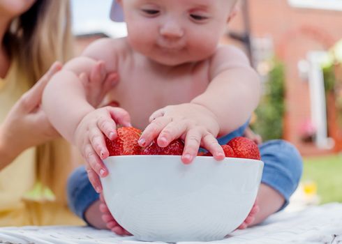 a child grabbing strawberries from a bowl