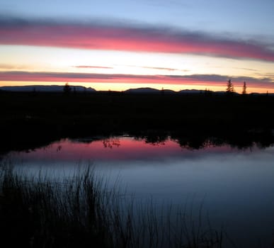 Sunset over the lake. Red sky and black horizon.