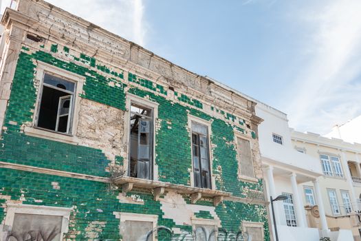 Albufeira, Portugal - May 3, 2018: People looking at a ruined building on the seafront in an upscale part of the resort town on a spring day