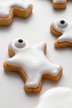 Close up of decorating cute Halloween gingerbread cookies with frosting icing cream topping bag.
