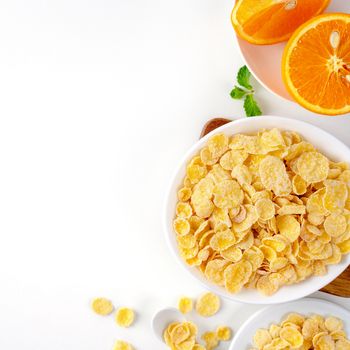 Top view of corn flakes bowl sweeties with milk and orange on white background, flat lay overhead layout, fresh and healthy breakfast design concept.