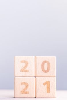 2021 New Year abstract design concept - Number wood block cubes isolated on wooden table and light mist blue background.