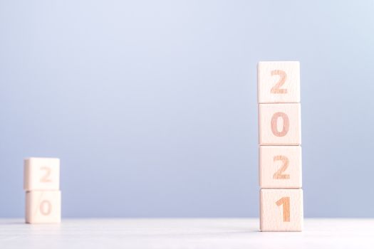 2021 New Year abstract design concept - Number wood block cubes isolated on wooden table and light mist blue background.