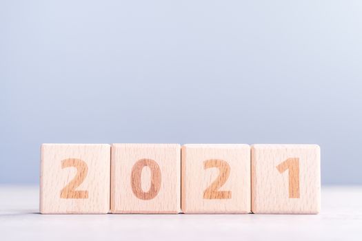 2021 New Year abstract design concept - Number wood block cubes isolated on wooden table and light mist blue background.