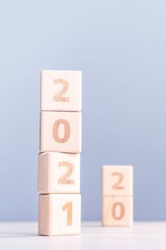 2021 New Year abstract design concept - Number wood block cubes isolated on wooden table and light mist blue background.