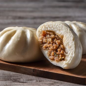Close up of fresh delicious baozi, Chinese steamed meat bun is ready to eat on serving plate and steamer, close up, copy space product design concept.