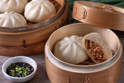Close up of fresh delicious baozi, Chinese steamed meat bun is ready to eat on serving plate and steamer, close up, copy space product design concept.