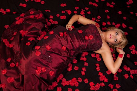 Attractive young woman in a red dress lying on back with flowers