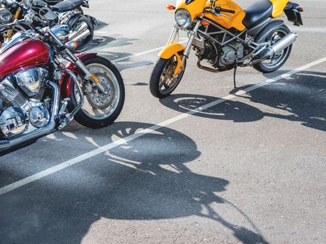 Motorcycles with shiny chrome parts are parked in the parking lot. Quite dangerous, but fast vehicle for moving around the city.