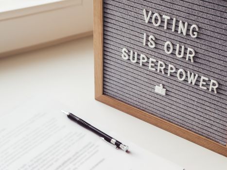 Letter board with phrase Voting is our superpower. Announcement of USA Presidential Election at 3rd November 2020. Call to go to the vote. Paper ballot and pen on window sill.