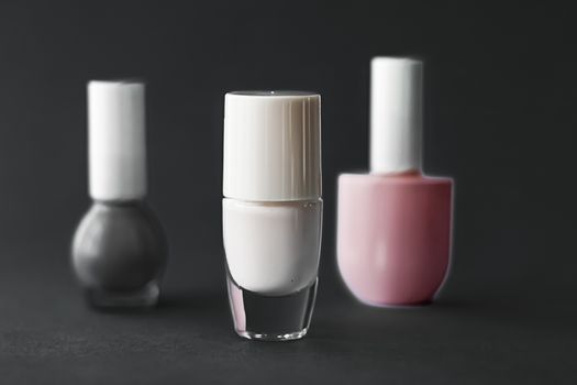 Nail polish bottles on black background, beauty branding