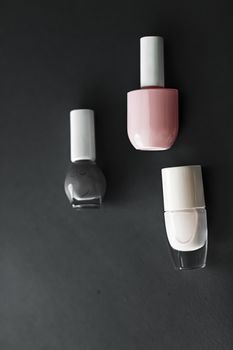 Nail polish bottles on black background, beauty branding