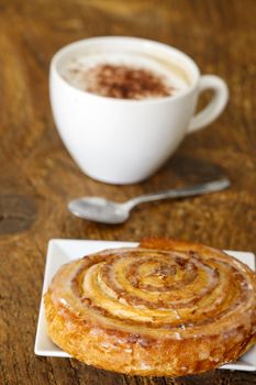 pastry roll with cappucino on wood