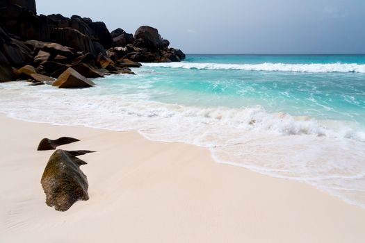 Blue sky and a white sand beach with a lot of big rocks