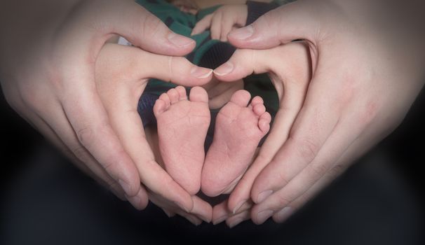 The Hands of adults hold small baby feet