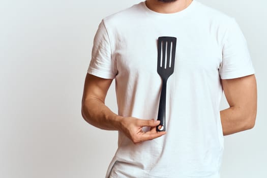 man with shovel for cooking white t-shirt cropped view light background. High quality photo
