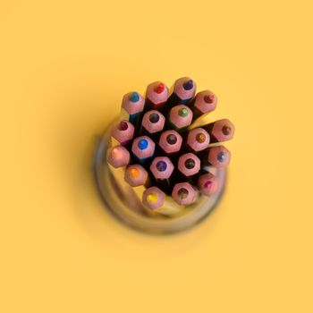 Сolored pencils in a jar on a yellow background