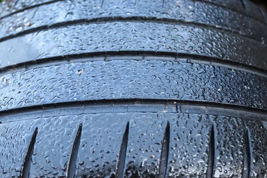 Black big tires in a close up view with water drops. Tire tread problems. Solutions concept.