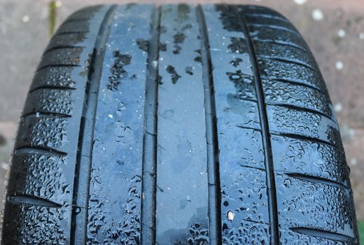 Black big tires in a close up view with water drops. Tire tread problems. Solutions concept.