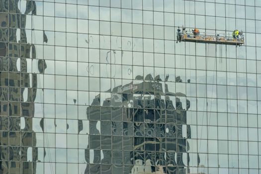 A group of engineers work on the outside of a skyscraper in a huge American city