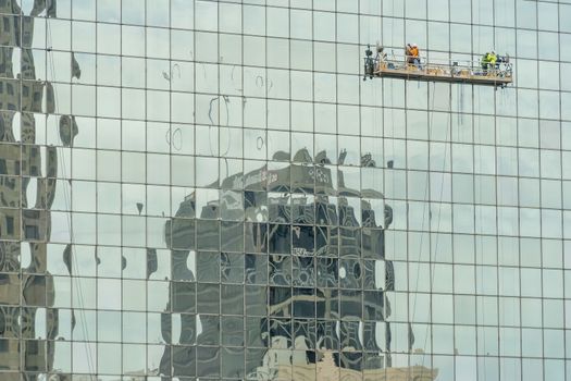 A group of engineers work on the outside of a skyscraper in a huge American city