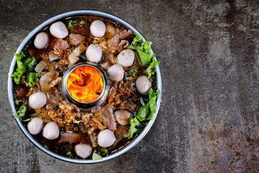 Thai style meat soup in a hotpot with vegetable on wood background