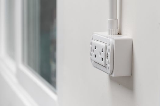 Close up of white plug on white room wall.