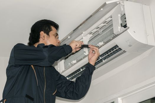 Air conditioner repairers in blue uniform are checking and repair air hanging on the wall.