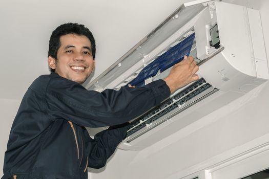 Air conditioner repairers in blue uniform are checking and repair air hanging on the wall.