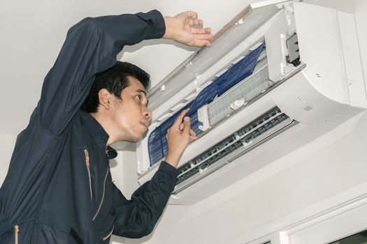 Air conditioner repairers in blue uniform are checking and repair air hanging on the wall.