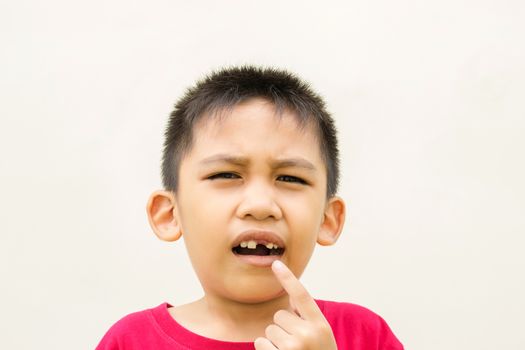 The boy is holding his hand on his cheek and red face with pain from toothache.