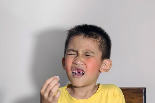 The boy cried out in pain as one of his teeth fell out and held it in his hand.