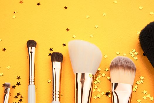 Makeup brushes in different sizes on a yellow background and glitter cropped look. High quality photo