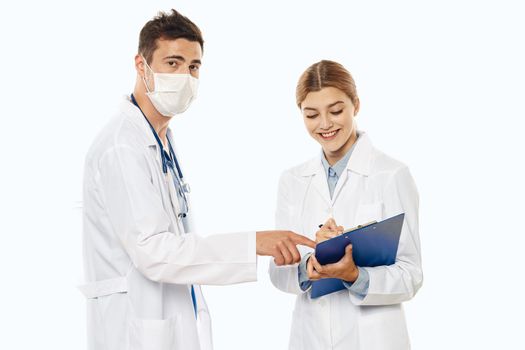 doctor and nurse in medical mask with documents in hand and gown isolated background