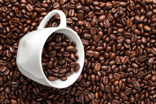 A White cup with coffee beans on a background of coffee beans
