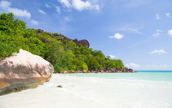 Beach with blue water and blue sky and white sand and some rocks