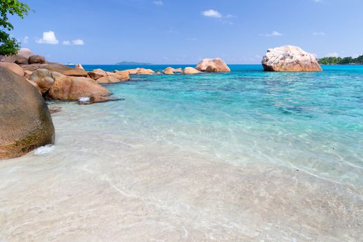 Beach with blue water and blue sky and white sand and some rocks